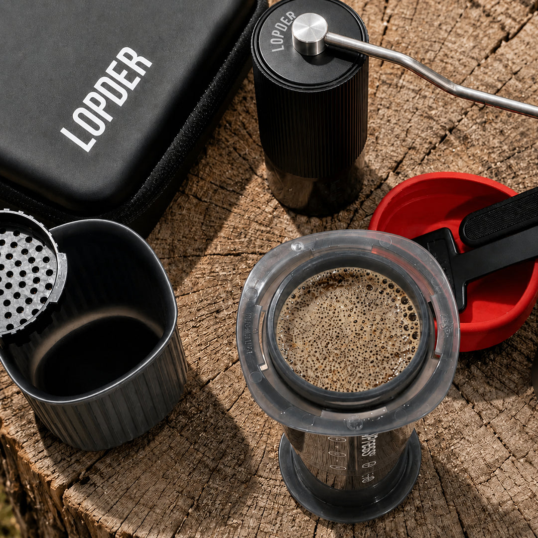Lopder MAXA manual grinder and travel case beside an AeroPress brewing setup
